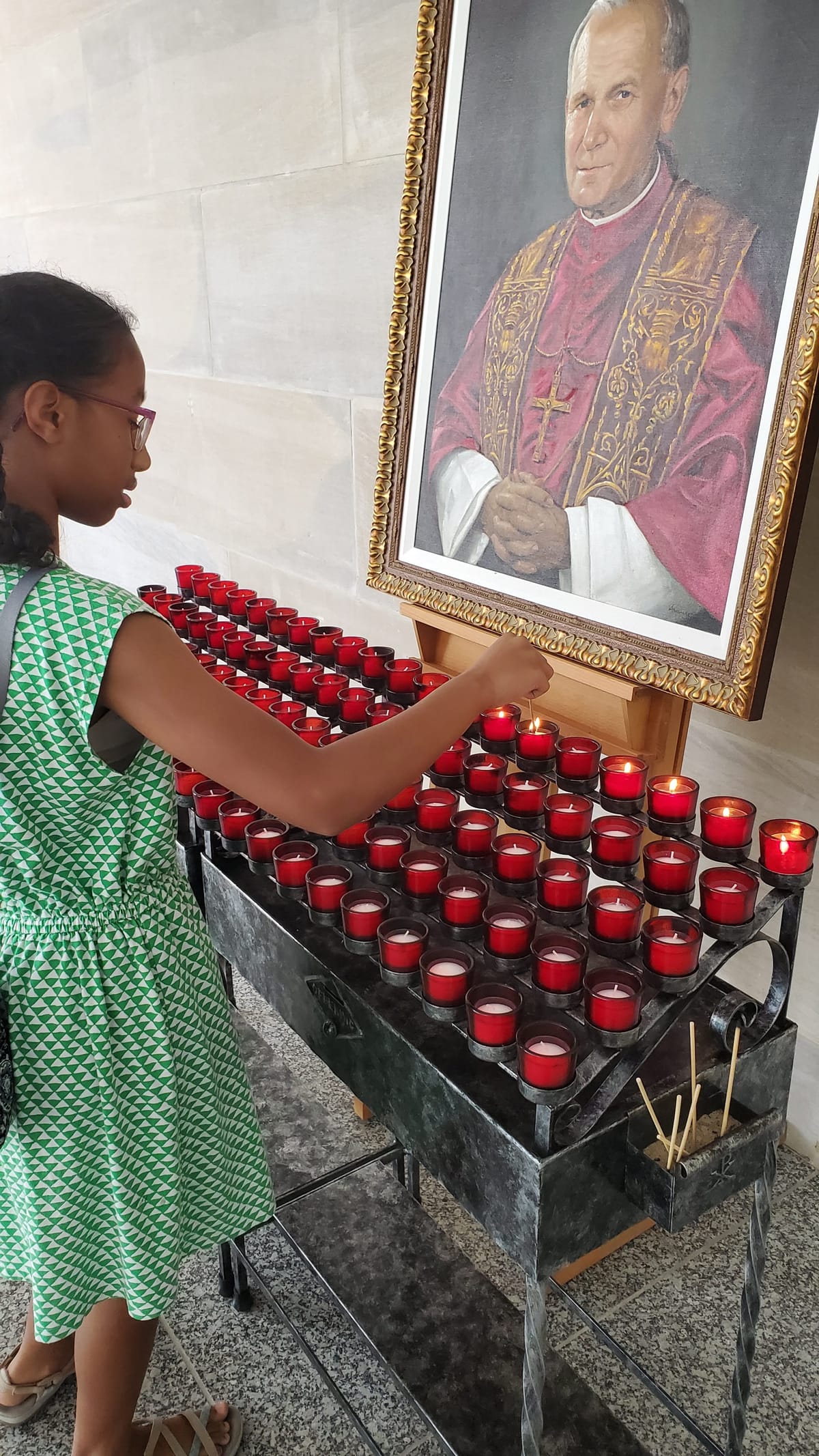 Black Girl Lighting A Candle at Pope Saint John Paul II Shrine - Catholic Stock Photo