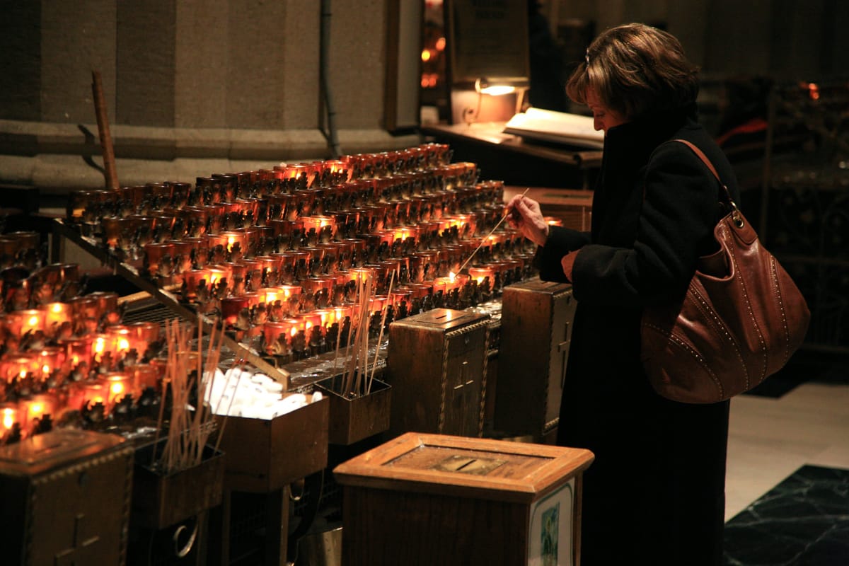 Woman Lighting Votive Candle at St. Patrick's Cathedral, New York - Catholic Stock Photo